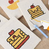 Mini punch needle kit showcasing dessert and pancake motifs on fabric pieces, perfect for beginners.