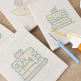 Mini punch needle kit with dessert and pancake motifs, showcasing colorful patterns on fabric with a punch needle tool.