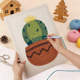 Person using a punch needle kit to create a colorful cactus in pot design on fabric.