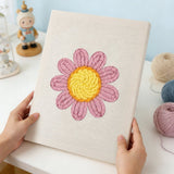 Punch needle kit featuring a pink daisy flower design on a textured canvas.